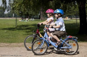 Dort, wo Kinder frei herumradeln dürfen, ist Radfahren nicht immer einfach - zum Beispiel auf den Kieswegen im Park. Auch in geschützen Bereichen ohne Autoverkehr sollte der Helm also ruhig getragen werden.